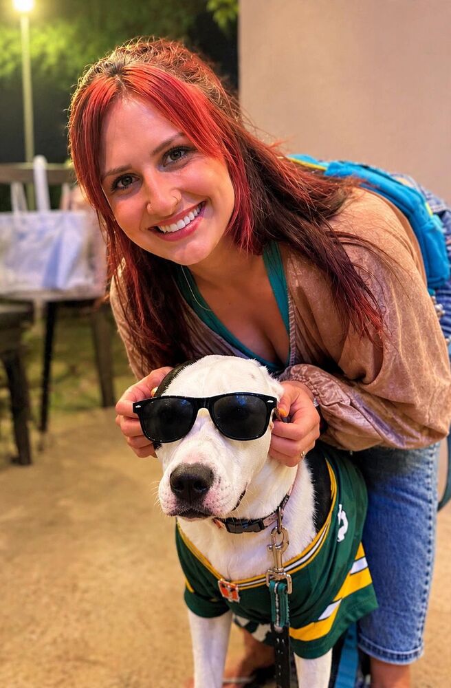 Kourtni smiling with a dog wearing sunglasses